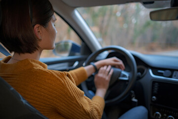 Asian young Woman behind the wheel of a car.