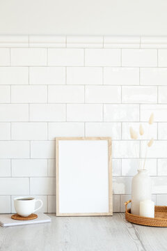 Breakfast still life. Blank vertical picture frame mockup, cup of coffee, vase of dried flowers, candles on table. Brick tiles wall on background. Hygge, nordic, Scandinavian style. © photoguns