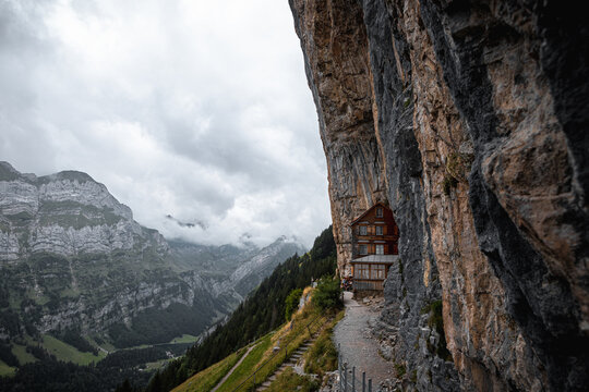 Typical mountain hut in the Alps (Aescher lodge) right next to a high rock formation on a cloudy and moody day (Appenzell, Switzerland, Europe)