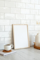 Picture frame mockup, cup of coffee, vase of dried flowers on wooden table. Nordic, Scandinavian style still life. Home interior design.