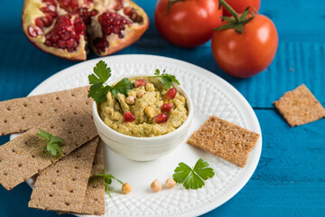 Vegetable appetizer hummus of Turkish chickpeas on a white plate with rye bread. Blue wooden...