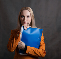 Business woman portrait with blue folder in hand on dark background.