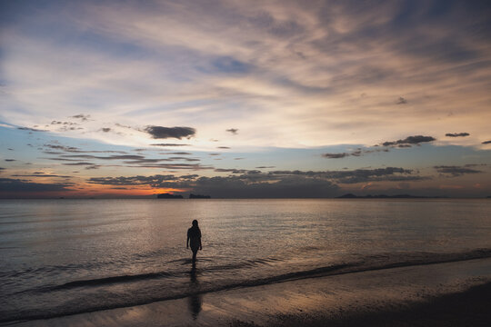 Silhouette image of a woman walking in the sea before sunset