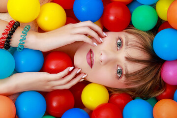 Fototapeta na wymiar Jeune femme allongée au milieu de boules de couleurs