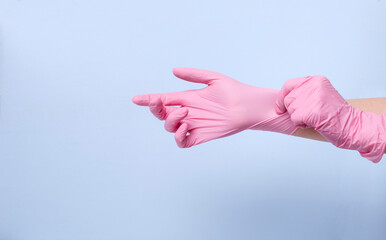 Woman wearing pink protective latex glovea against blue background