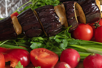 Grilled eggplant with fresh vegetables. Baked vegetables on a wooden plate.