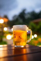 Glass mug of fresh cold beer on the table in summer terrace