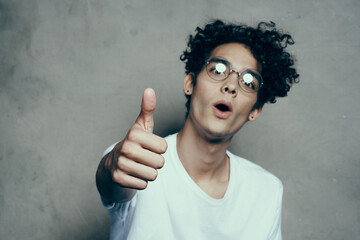 Cheerful cute guy with curly hair shows thumb up emotions