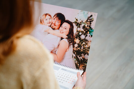 A woman looks at a calendar with a family photo. 