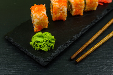 Sushi roll philadelphia with salmon, rice, cheese, cucumber, avocado and caviar on a slate board. Japanese food