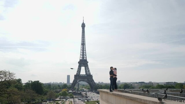 Newlywed couple kisses on parapet against Eiffel Tower