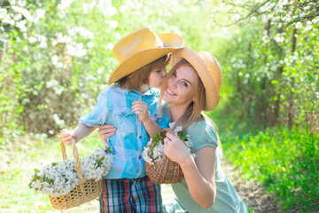 Spring family outdoor. Mother son family at spring day on picnic. Family mom with kid boy sitting on the grass in park with basket of flower bloom blossom.