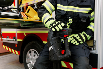 Fototapeta premium A man of strong physique in uniform and helmet stands by a rescue vehicle.