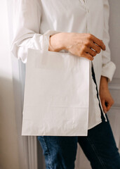 Closeup of a woman holding a white blank paper bag.