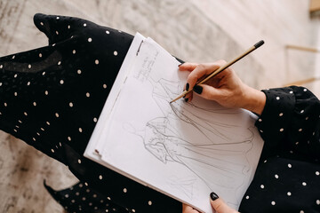 Closeup of a fashion wedding designer sketching new bridal dresses with a pencil.