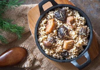 Barley porridge with, meat, mushrooms in a frying pan