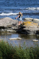 A girl climbing on stones by the sea at Fårö, Gotland Sweden.