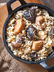 Barley porridge with, meat, mushrooms in a frying pan