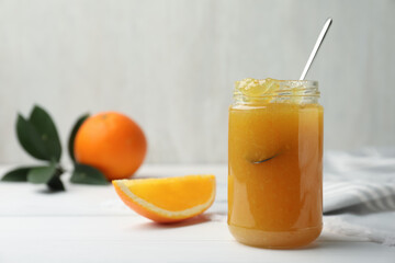 Delicious orange marmalade in jar on white table, space for text