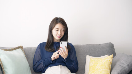 部屋でリラックスしてスマホを見る女性