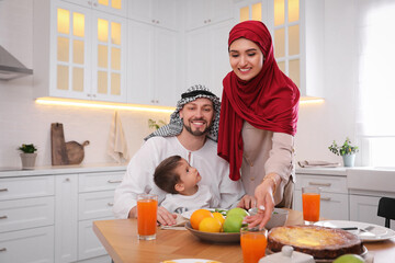 Happy Muslim family eating together in kitchen