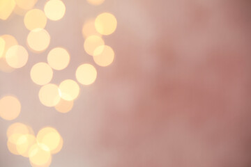 Blurred view of gold lights on pink background, bokeh effect. Space for text