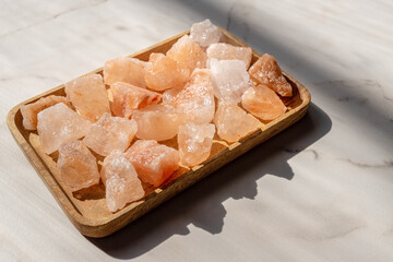 Crystals of Pink himalayan salt on wooden tray, interior deoration, spa and heath care concept