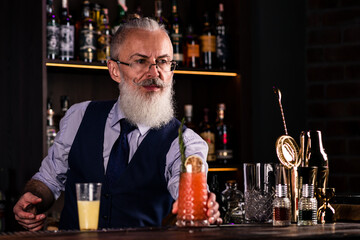 Elderly bartender gives red cocktail. Fresh cocktail alcoholic, non-alcoholic drink-beverage at the bar counter in the night club