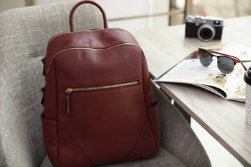 Stylish backpack on grey chair near table indoors