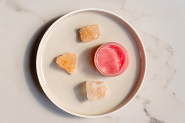 Himalayan salt and pink body or face scrub on ceramic round tray on marble background. Bath salt. Spa treatment. beauty and relaxation concept.
