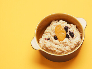 Delicious organic porridge with blueberries and apricot on a yellow table