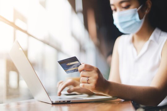 woman wearing surgical mask and using laptop. - Powered by Adobe