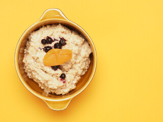 Delicious organic porridge with blueberries and apricot on a yellow table