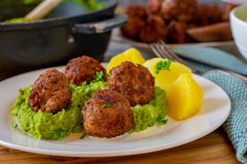 Meatballs with pea puree and potatoes on a plate
