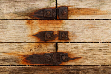 Old rusty bolts screwed into grunge wooden planks