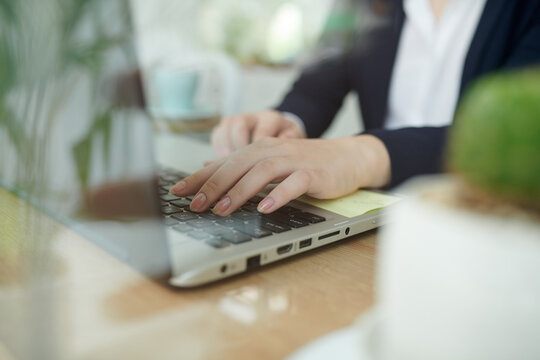 Close-up image of businesswoman typing on laptop, answering e-mails, checking documents and sending reports