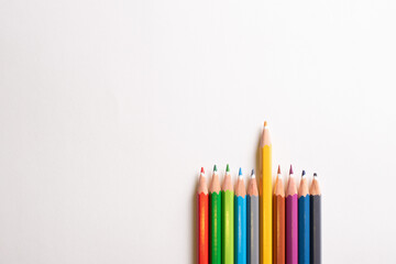 Top view of colored pencils side by side highlighting the yellow pencils on the white background.