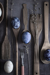 Easter concept. still life flat lay. Eggs dyed with natural dye lie on wooden spoons on a dark concrete background.