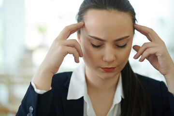 Pretty young female entrepreneur suffering from severe headache or migraine after working all day