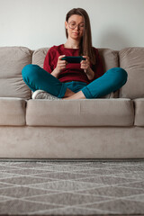 Obraz premium Woman using mobile phone, holding in hands sitting on sofa