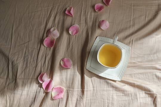 a cup of tea with rose petals on the bed sheet, breakfast in bed for your beloved