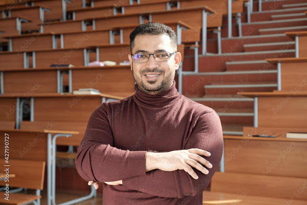 Aufkleber young successful male teacher of university crossing his arms by chest while standing in front of ca