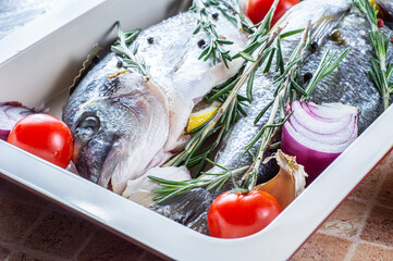 Raw dorado fish with spices cooking on cutting board. Dorada and ingredients for cooking on a table.