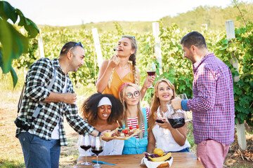Happy friends having fun tasting red wine in vineyard