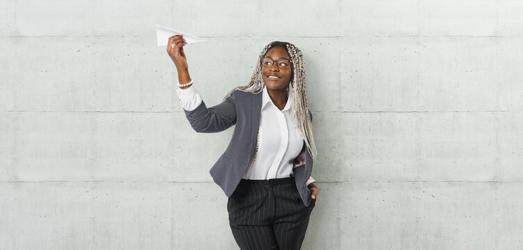 Young beautiful african woman holding hand model paper air plane. Design of travel concept with air plane on empty gray color background