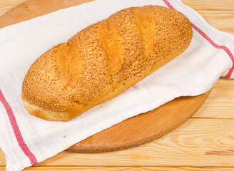 Wheat bread sprinkled with sesame on napkin on rustic table