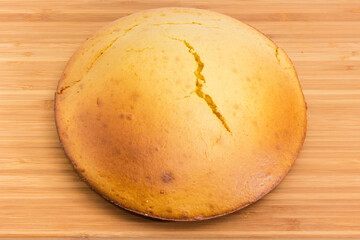Baked homemade round sponge cake on wooden surface