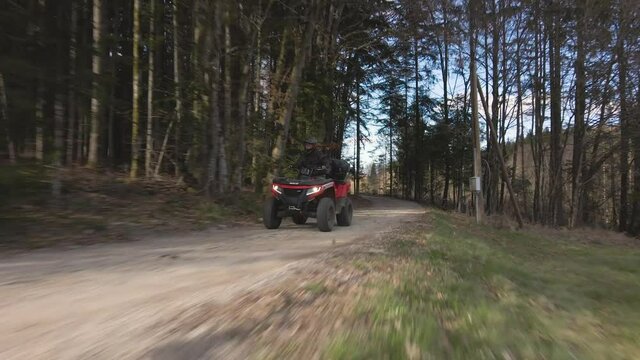 A man riding his quad bike - ATV through the woods on a sunny day - 4k footage
