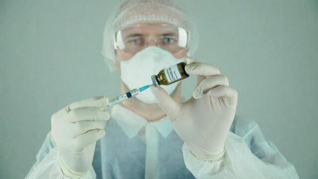Doctor or biologist filling syringe with needle holding vaccine with liquid drug in lab. Medicines research concept and defeating dangerous covid-19 infection