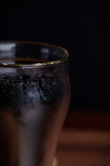 close up ice cola in glass and bubble soda on black